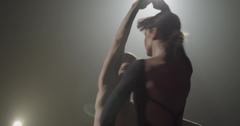Woman pirouettes while helped by male