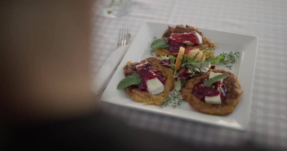 A plate of food is placed on a table and the person picks up the utensils