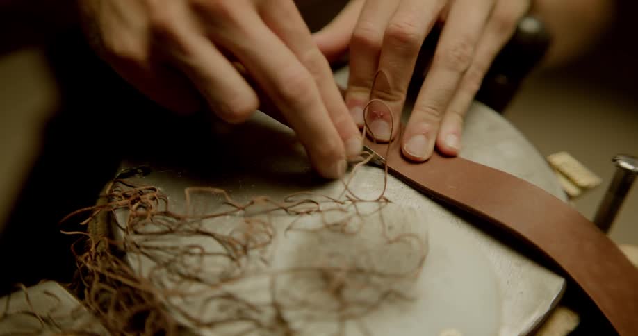 A man filing a strap of leather