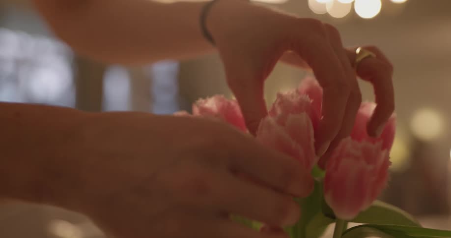 A person fixes flowers in an arrangement