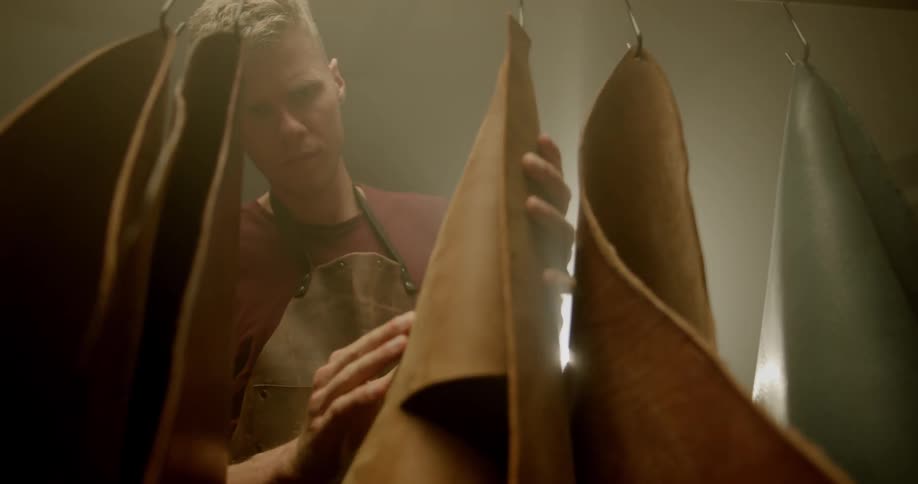 Man feels grain of hanging piece of leather