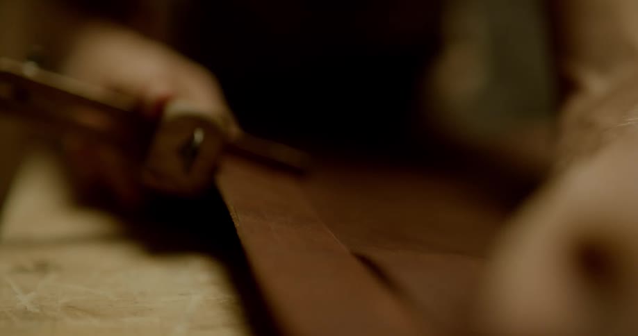 A man cuts a strip of leather