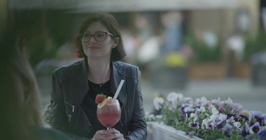 A woman is outside holding a drink