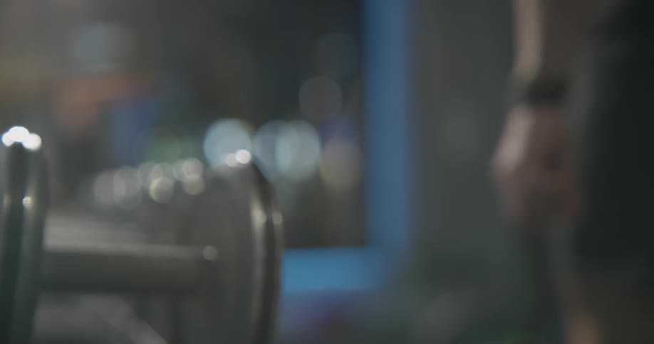 A man picks up a dumbbell from a row of dumbbells