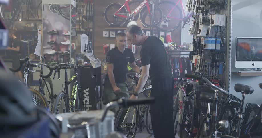 Two men examine a bicycle in a bike shop