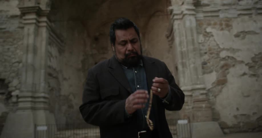 A man exits an ancient church with a necklace in his hands