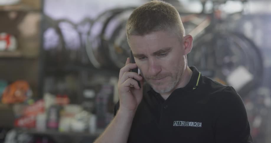 A bicycle shop employee uses the phone
