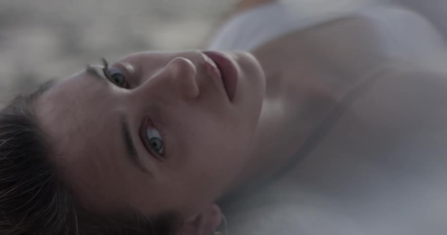 A woman is laying down and tilts her head back