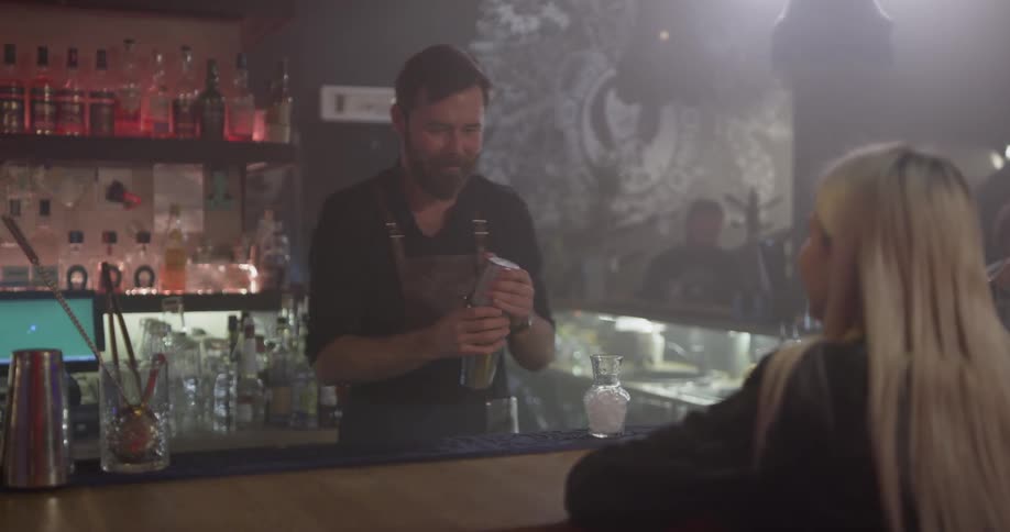 A bartender vigorously shakes a boston shaker