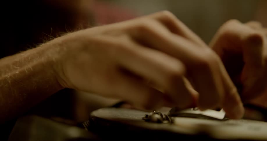 A man sits down and places a buckle on a leather belt