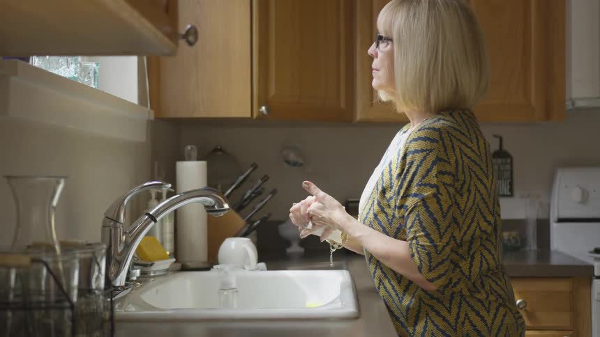 A woman cleaning dishes at a kitchen sink