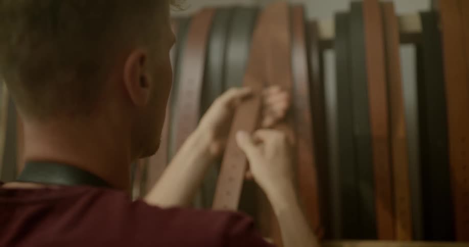 A man grabs a light brown leather belt