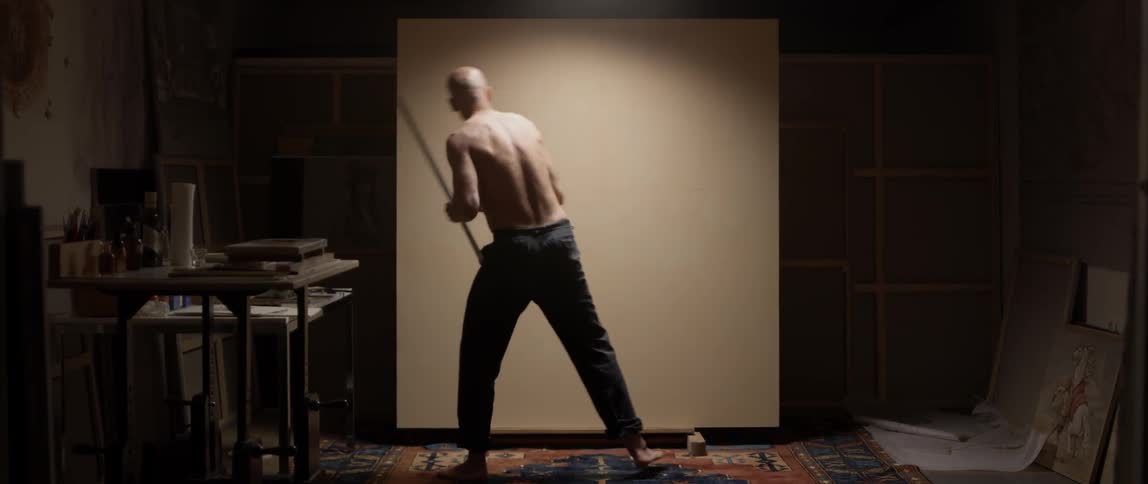 Shirtless man wearing pants with yardstick measuring wall