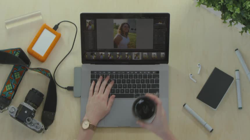 Person works on laptop and takes sip of mug