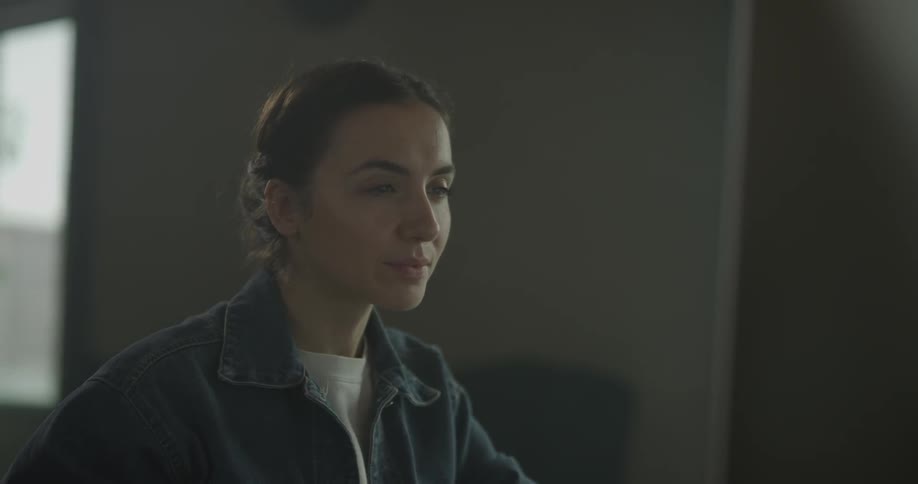 A woman is seated while looking at a monitor