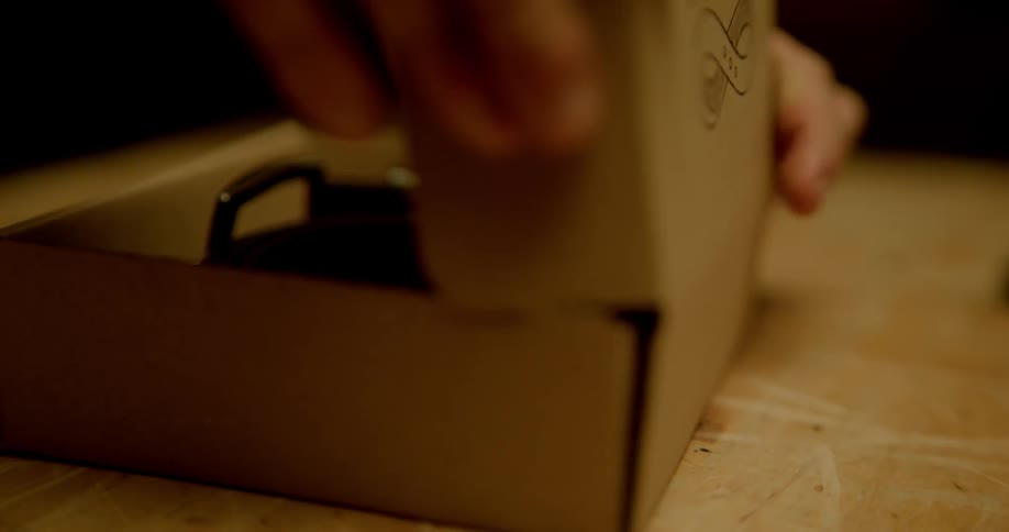 A person places items in a cardboard box and closes it