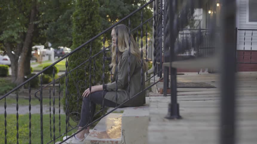 A woman sits on the steps of a house