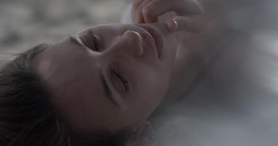 Woman lays on the ground touching her chin