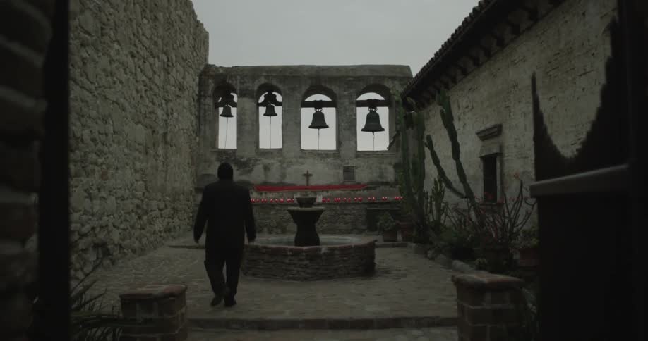 Man walks towards a ledge of candles outside a church