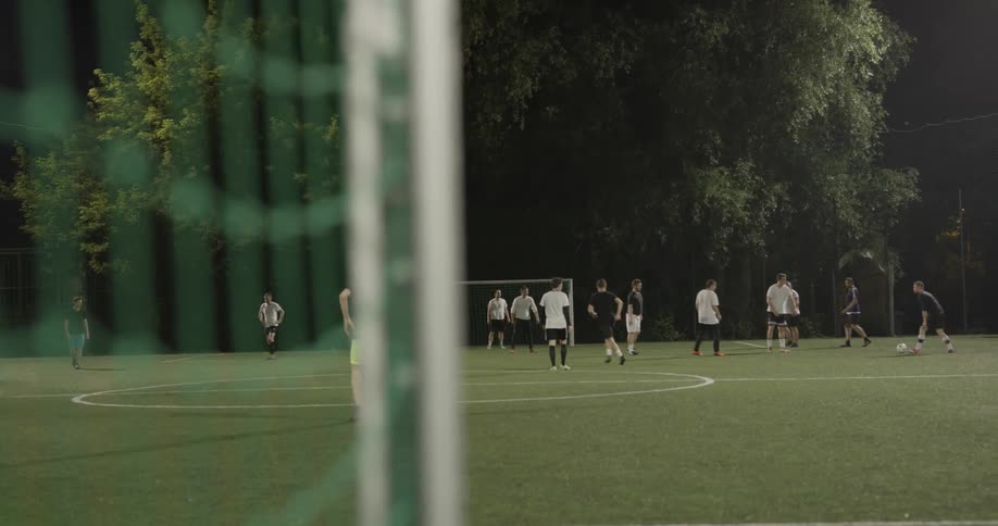 Soccer players compete on an outdoor field at night
