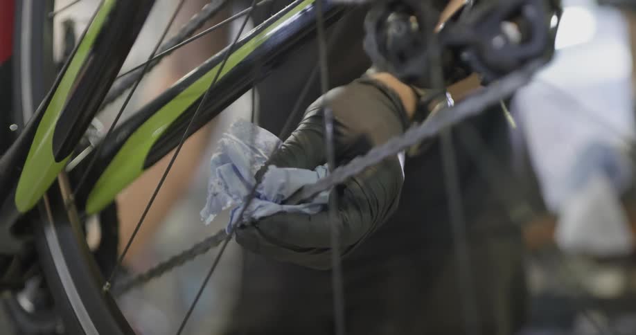 Person wipes grease off a bike chain with a rag
