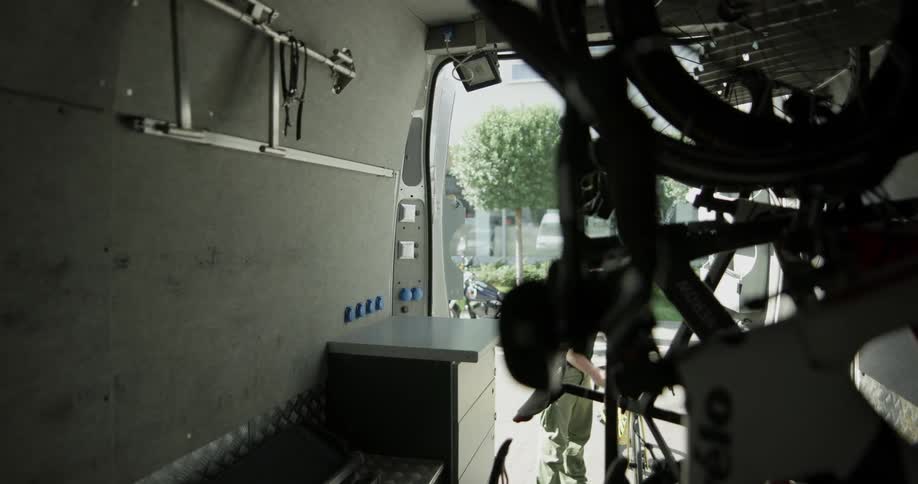 A man putting a bicycle into the back of a van