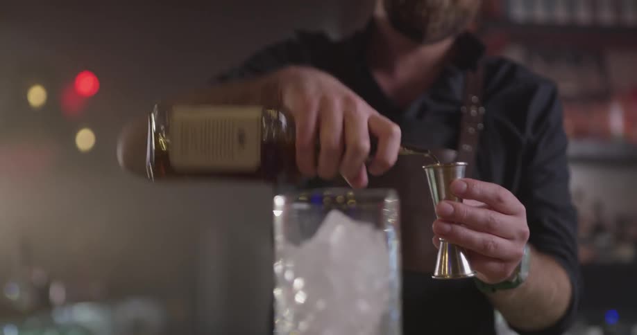 A man is pouring liquid into a glass of ice