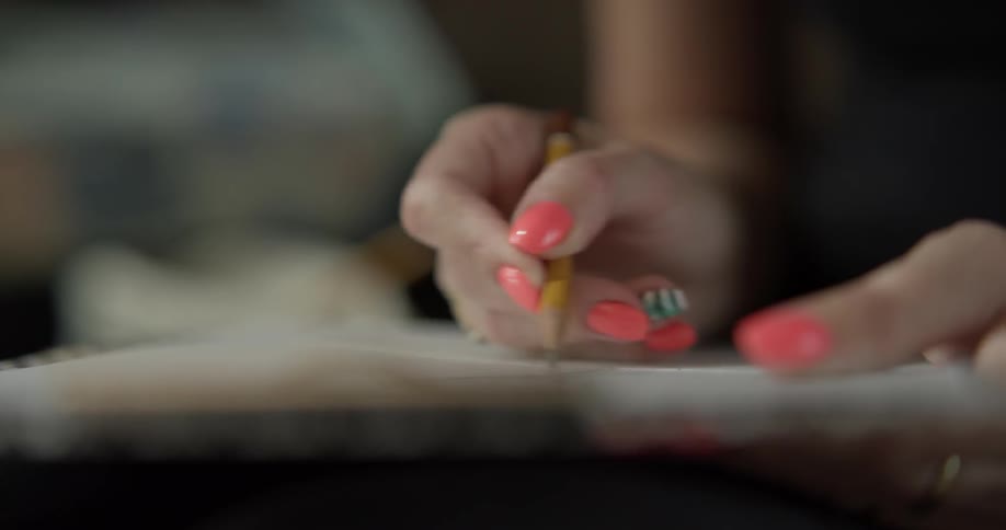 A woman is drawing on a piece of paper with a pencil