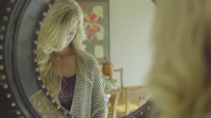 A woman is looking at herself in a mirror