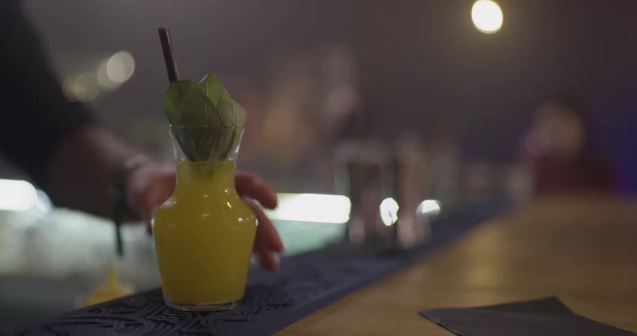 A bartender makes a cocktail and hands it to his patron
