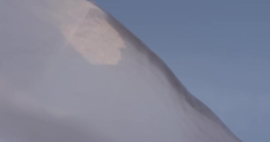 Thin white cloth waves around in the wind with human hands waving over the blue skies of a bright sunny day