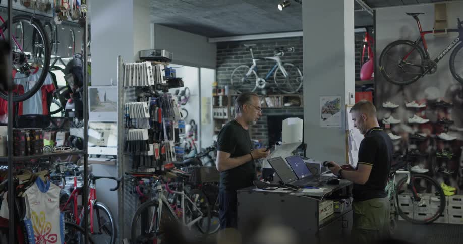 Two men in a bicycle shop and one looks like the clerk