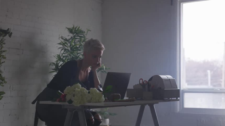 A blonde, short-haired florist works at her till