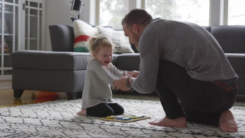 Man plays arm wriggling game with toddler on rug