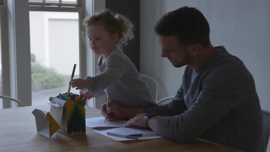 Father and daughter coloring at a kitchen table