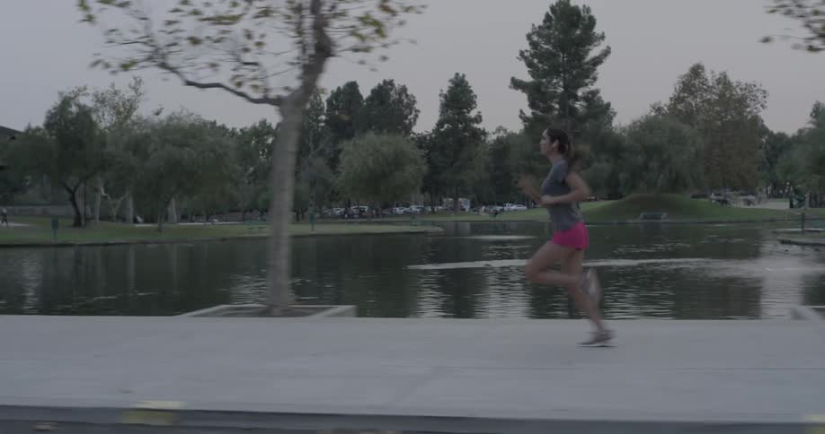 A woman is jogging outside by a park