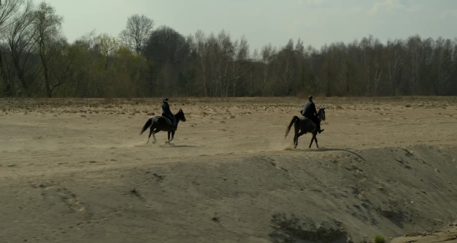 Two people are riding horses by the beach