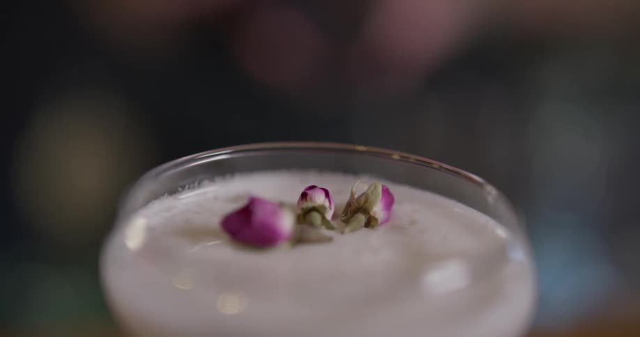 Someone garnishes a drink with flower buds