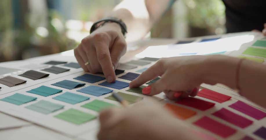 Two people pointing at different paint color options