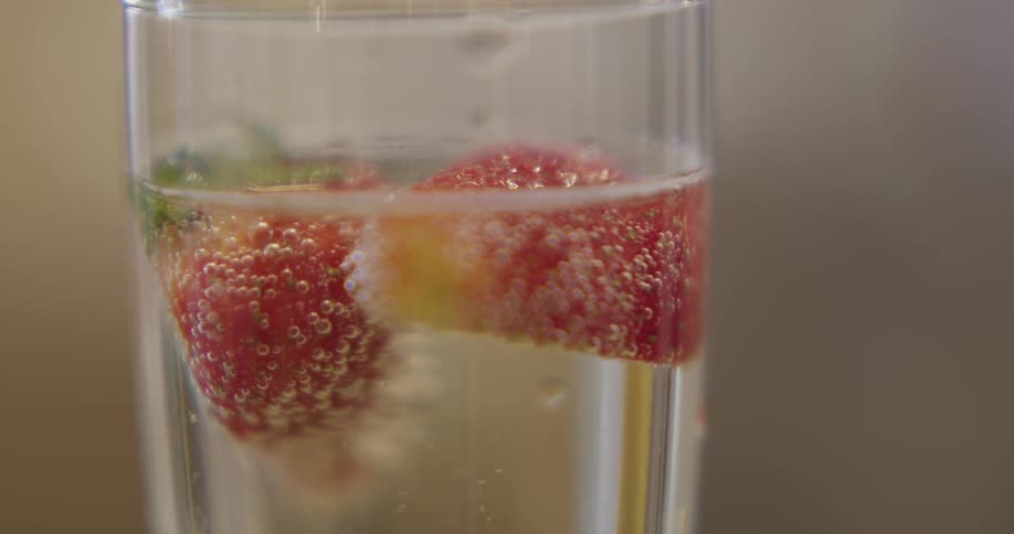 Champagne bubbles are rising around strawberry slices in a champagne flute