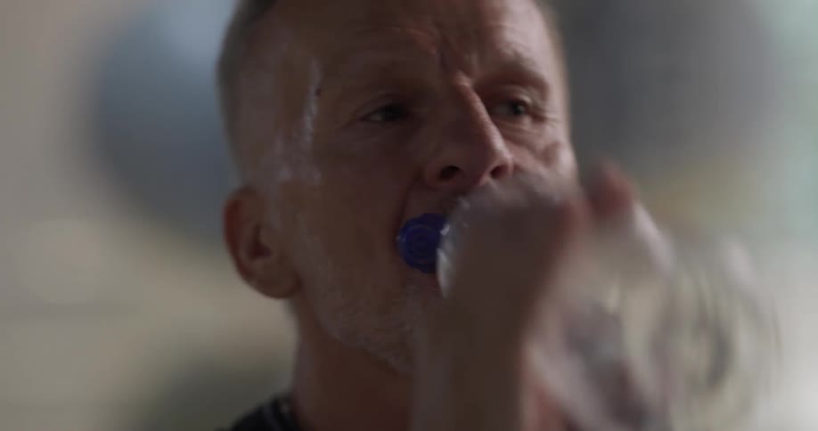 Older man taking sips out of a water bottle