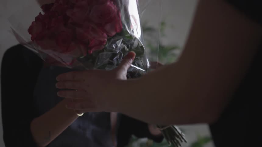 A woman handing a bouquet to a man in a store