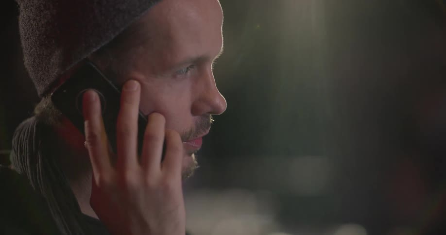 A man wearing a hat and scarf talks on his phone
