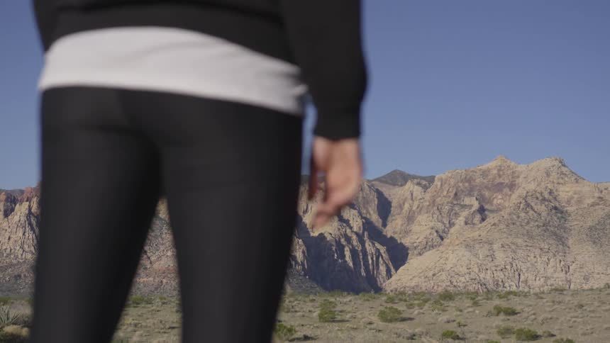 Person stands in the desert facing towards rocky hills