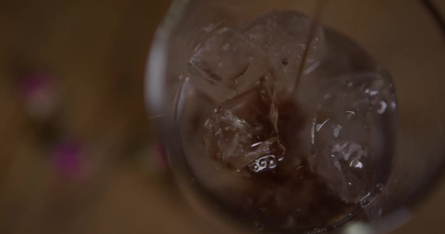 Liquid is being poured into a glass of ice