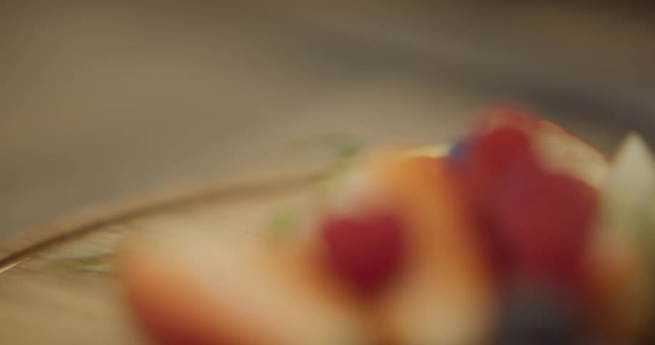 A person picks up a cutting board with fruit