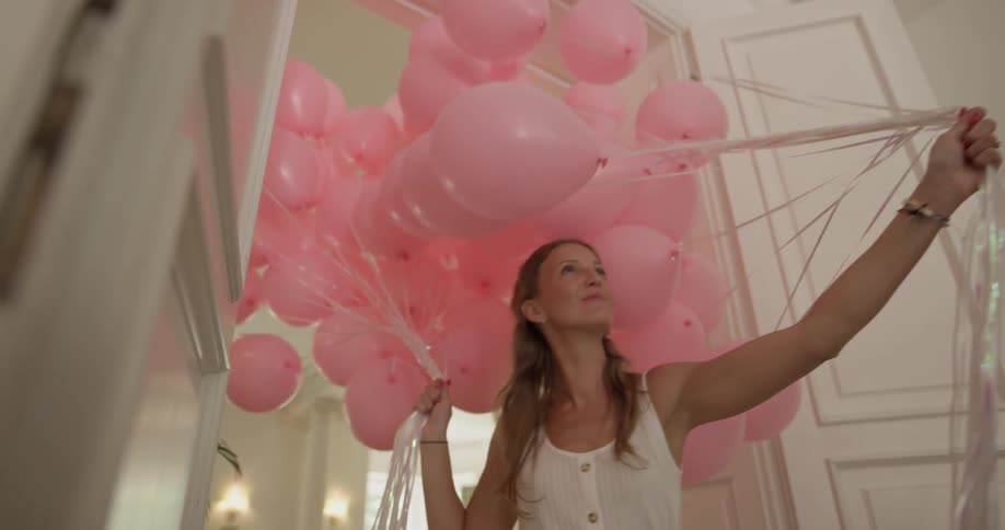 A woman carrying balloons into a room