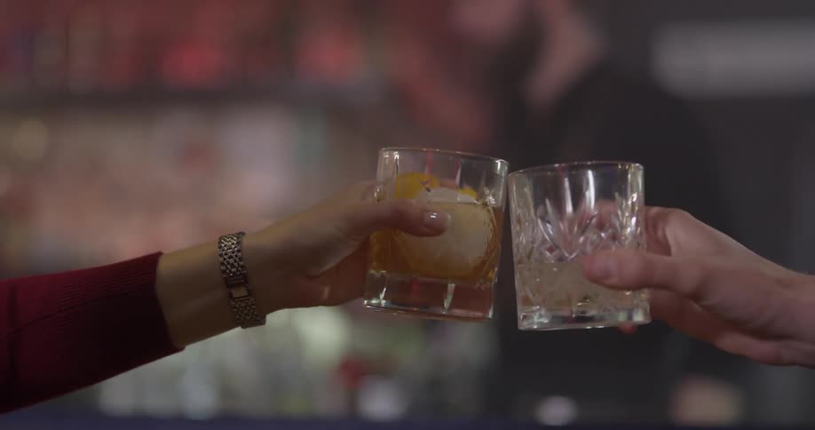 Two people sit at a table and clink glasses