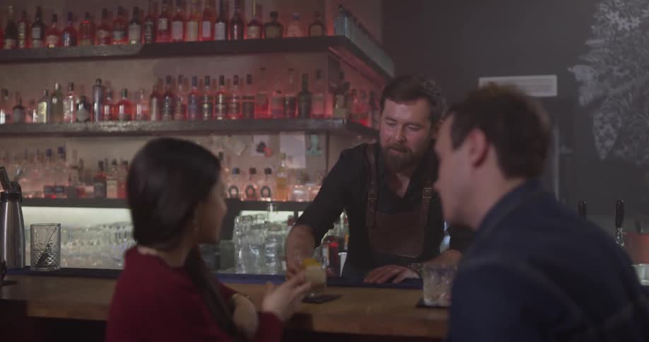 Two people are being served drinks at a bar