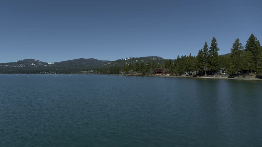Water flows in a wide river lined with hills and trees